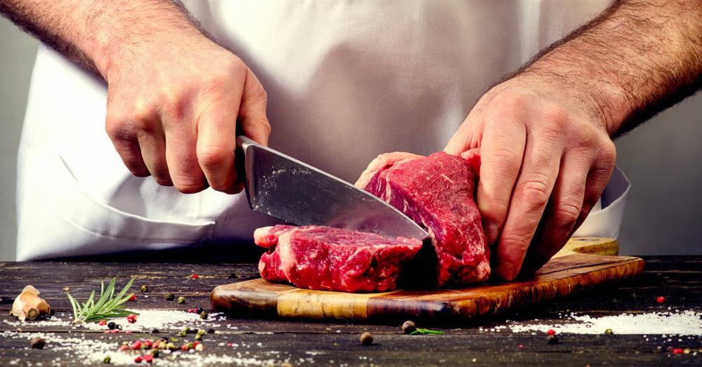 Un homme coupant du boeuf